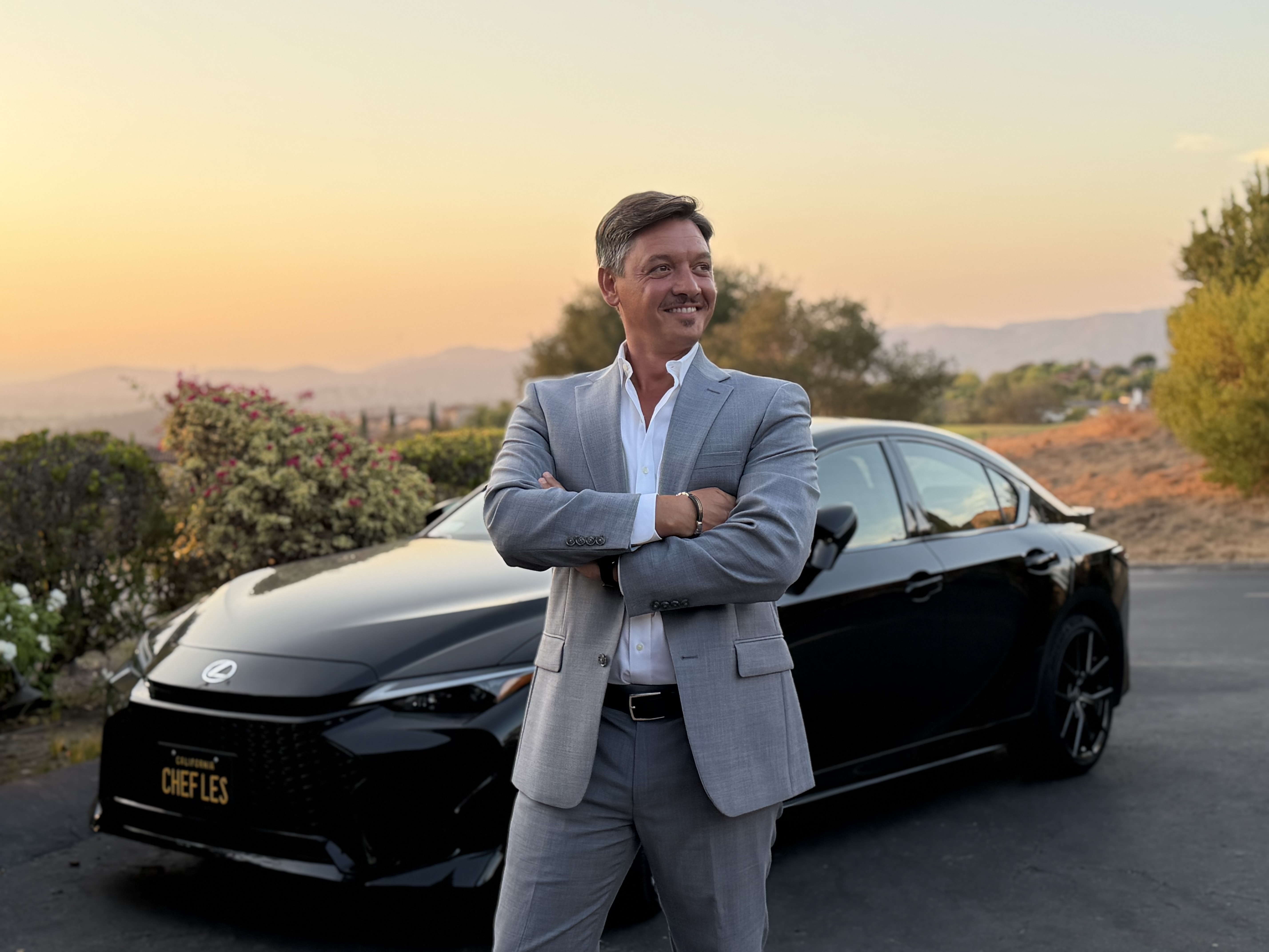 Fabio Stallone beside a black Lexus at sunset